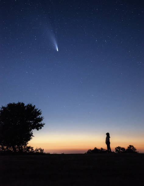 istock Young woman watching the Neowise comet under the bright night sky 1257362144