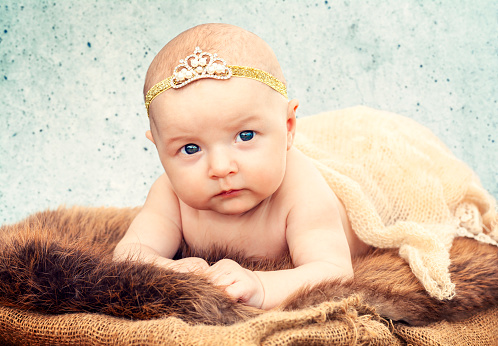 Little Princess - photo studio session. A photo of a newborn baby dressed as a princess in a crown. Lying on an animal fur.
