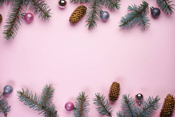 istock Spruce branches with cones and Christmas decorations on a pink background, with space for text, top view. 1257363990