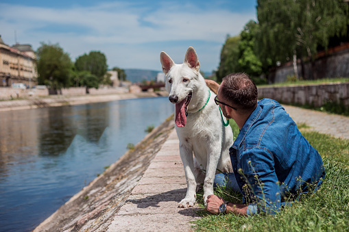 Young man and his white dog relaxing by the river