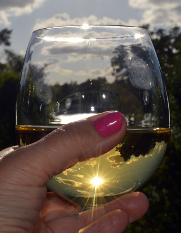 Stunning lake view reflected in a glass of white wine a warm summers night.