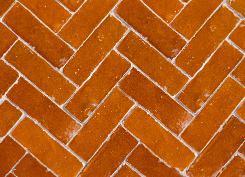 A crop shot of an old herringbone brick tile texture in orange color