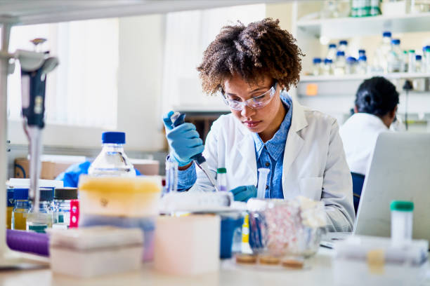 Young scientist using a pipette to analyzing a sample in a lab Young female scientist sitting at a table in a lab using a pipette to analyze a sample while working in a lab science and technology lab stock pictures, royalty-free photos & images