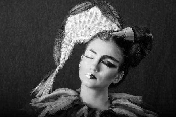 istock Caucasian Brunette with Half Face Painted with White and Half Graphic Black Make-up, Closing Her Eyes, in Black and White. Angel and Devil Concept 1257374049