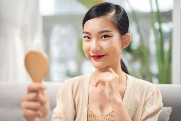 istock Asian woman looking at her face in mirror 1257375897