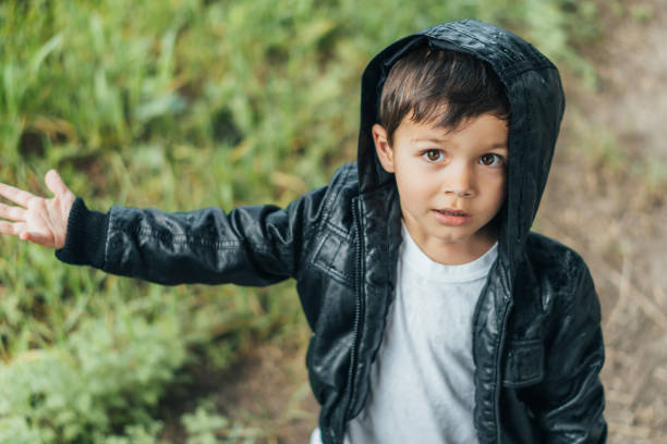 istock high angle view of cute boy in black jacket looking at camera 1257380745