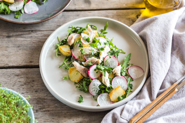 Fresh salad with radishes, potatoes, arugula and mackerel or tuna. diet concept stock photo