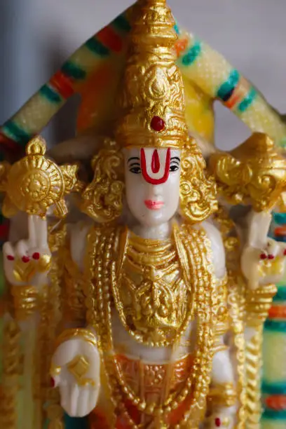 Photo of Colorful Painted Golden Yellow Color Handcrafted Statue Of Indian Hindu Lord God Idol Sri Sreenathji Vishnu Tirupati Balaji Or Venkateswara Made Of Earthenware Mud Clay Stone Or Rock In Standing Position And Blessing Pose For Worship Pooja Puja In Festiva