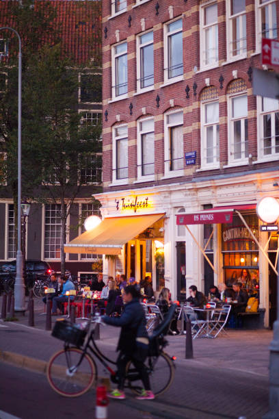 Nughtlife scene at bar in Wallen of Amsterdam in autumn Nightlife scene at bar in Wallen of Amsterdam in autumn. People are sitting outside of a bar. Scene is at Geldersekade, asmall square. Name of bar is 't Tuinfeest. At right side is mexican restaurant. wellen stock pictures, royalty-free photos & images