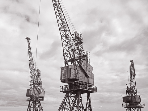 An old cargo cranes against dramatic and cloudy moody sky.