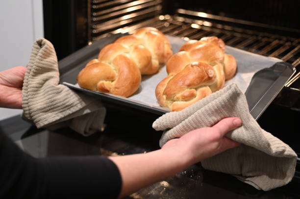 jewish woman taking out baked challah bread out of the oven - challah imagens e fotografias de stock