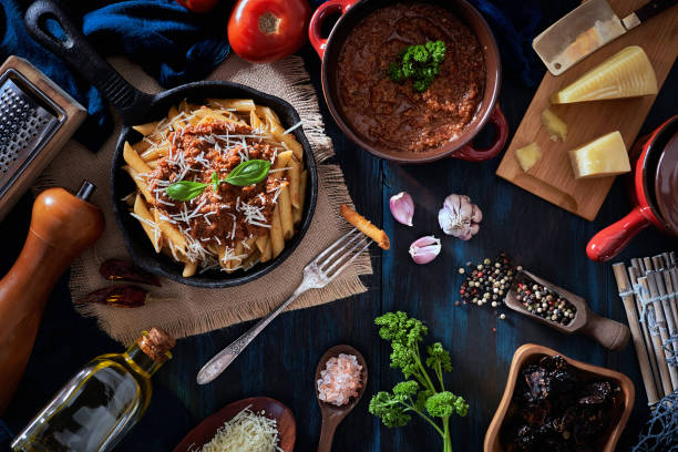 istock Penne with Bolognese sauce in serving size casserole with ingredients in rustic pots 1257384522