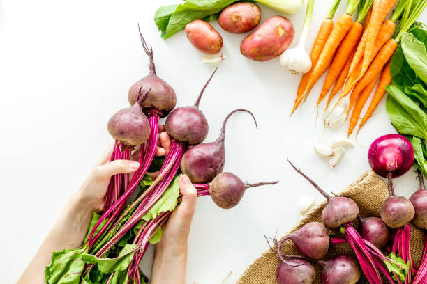 Harvest of vegetables. Hand hold beet with green tops top view