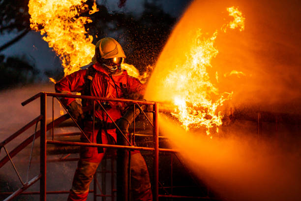 bomberos que utilizan niebla de agua rociando fuego de la explosión de la fábrica de plataformas petrolíferas - protective suit fotografías e imágenes de stock