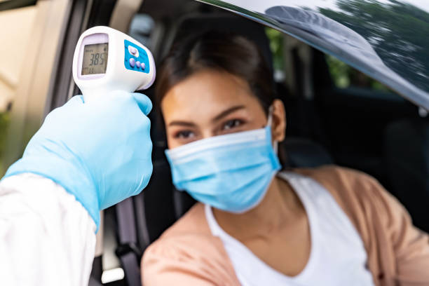 Medical staff take temperature drive thru service Medical staff with PPE Take Temperature for fever to asian woman before coronavirus covid-19 test at drive thru station in hospital. New normal healthcare drive thru service and medical concept. covid thermometer stock pictures, royalty-free photos & images