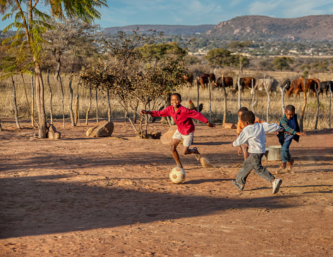 African children playing soccer on the dirt in his yard in a village in Botswana