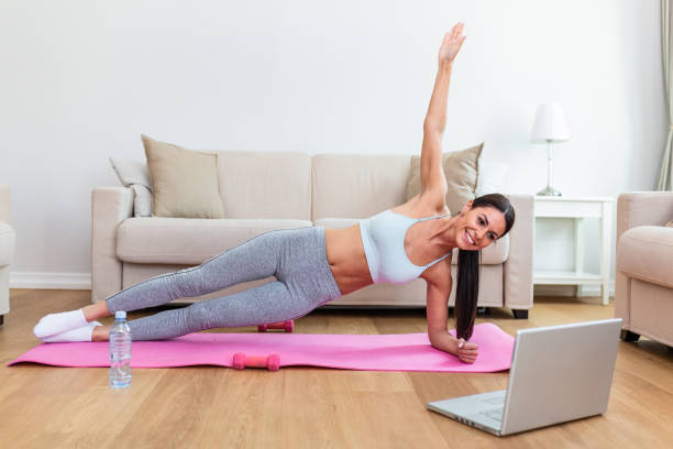 istock ortrait of young attractive woman doing exercises while watching online lessons on her laptop. Healthy lifestyle and sports concept. Shot of fitness woman sitting on exercise mat 1257390077