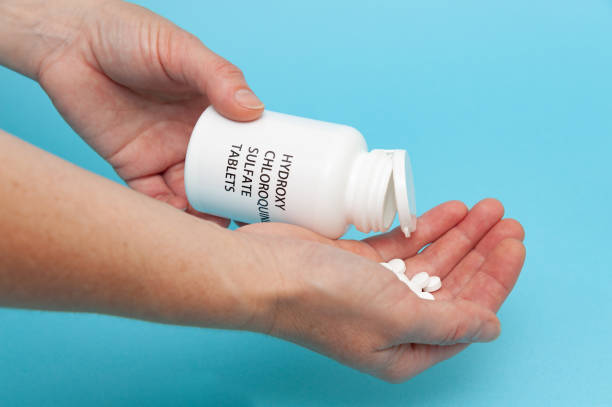 istock Treatments for Coronavirus (COVID-19): Hydroxychloroquine Sulfate - White plastic packaging bottle in the hands with tablets. 1257390100