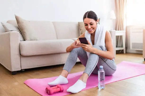 Young beautiful women resting and refreshment after exercising workout and using smart phone, checking social media on her phone and resting from exercises