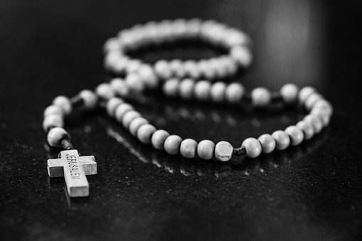 Beautiful Catholic rosary  lying on surface isolated and in black and white.