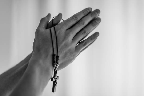 manos de hombre cristiano que ora mientras sostiene un colgante con un crucifijo. - confession booth penance catholicism church fotografías e imágenes de stock