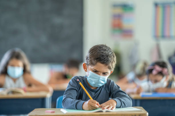 istock Young boy wearing a protective mask in classroom 1257395068