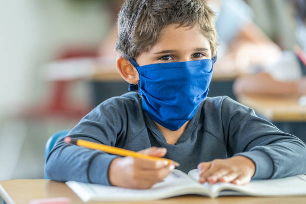 istock Young boy wearing a protective mask in classroom 1257395083