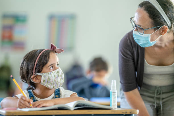 istock Young girl wearing a protective face mask in classroom 1257395107