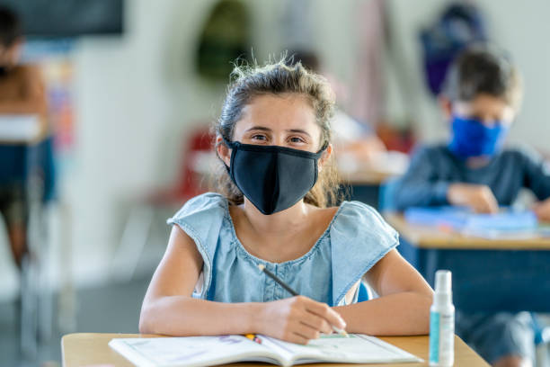 istock Young female student wearing a protective face mask in the classroom 1257395121