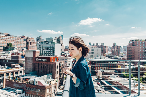 Big city. Big Dreams. City planning. Side view shot of a young female architect looking out at rooftop in Manhattan, NYC.