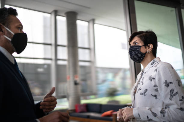 istock Coworkers talking on office's lobby - with face mask 1257397800