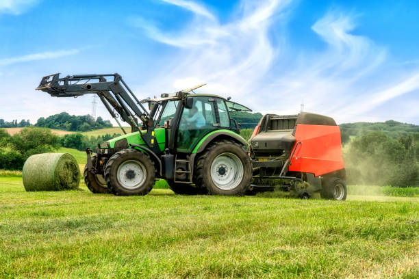 Big baler with film wrapper in use for grass silage preparation Big baler with film wrapper in use for grass silage preparation hay baler stock pictures, royalty-free photos & images