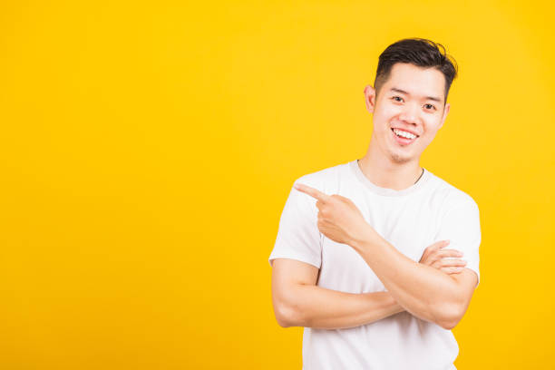 istock young man smiling standing pointing finger to the side away 1257398299