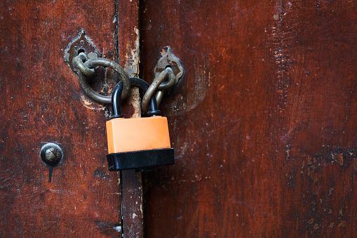 Locked wooden door. Closed for coronavirus pandemic quarantine. Old wood door with locked padlock