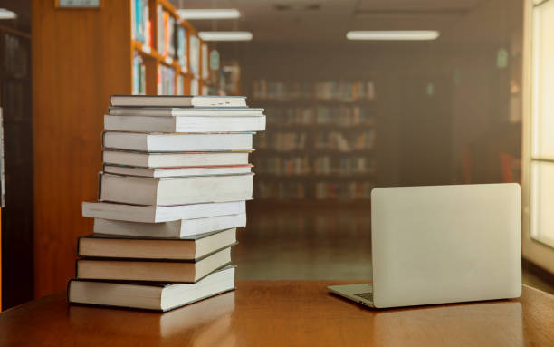 istock Stack of old books and laptop computer on desk in library background. Educational technology concept. 1257401485