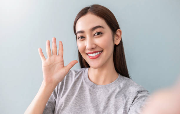 retrato de joven hermosa mujer asiática usando selfie teléfono inteligente decir hola sobre el fondo blanco. feliz chica asiática en línea influencer blogger. tecnología educativa conectada a las personas concepto de estilo de vida de mujer - statue human face women human skin fotografías e imágenes de stock