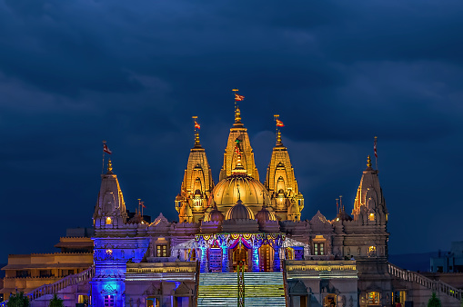 Imagen iluminada del templo Shree Swaminarayan con nubes monzónicas de fondo, Ambe Gaon, Pune. photo