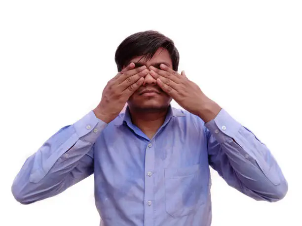 male cover eyes with his both hands wearing blue shirt on White background.