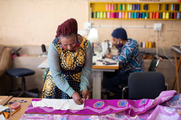 An African woman cutting patterns in fabric in her studio.