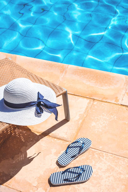 istock White summer hat with marine flip flops at swimming pool in summer 1257413218