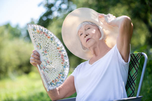 Woman relaxing in a deck chair with a fan