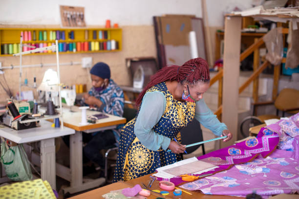 An African woman cutting patterns in fabric in her studio.