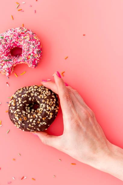 istock Hand holding glazed donut swith sprinkles, above view 1257416373