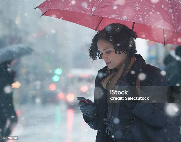 Joven Mujer Enviando Mensajes De Texto En La Nieve Foto de stock y más banco de imágenes de Mujeres - Mujeres, Paraguas, Ciudad