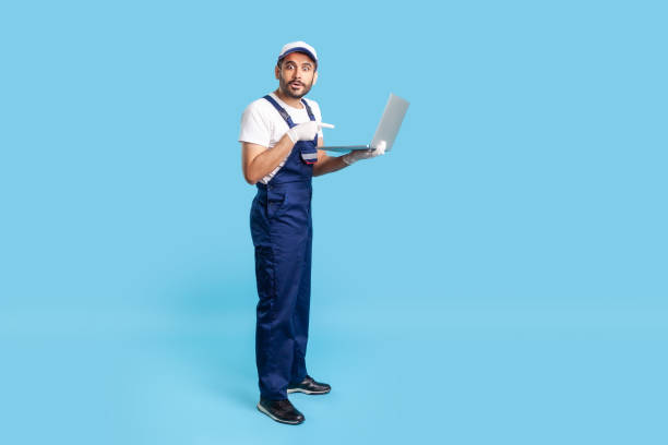 istock Full length amazed workman in uniform pointing at laptop and looking with shocked expression 1257418310