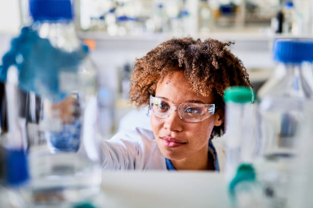 istock Young female scientist selecting a sample bottle from a lab shelf 1257418756