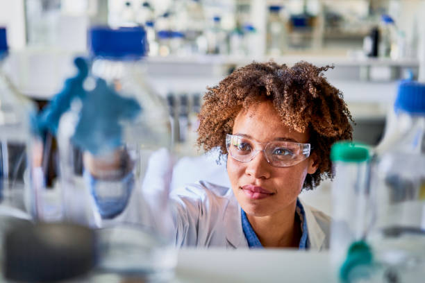 istock Young female scientist selecting sample bottles from a lab shelf 1257418867