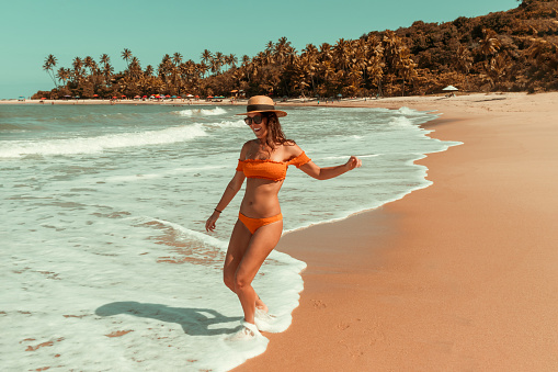 Girl running at the beach, enjoying vacations on tropical scenery. Girl in bathing suit