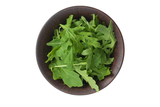 istock Fresh leaves of arugula in ceramic brown bowl isolated. 1257426510