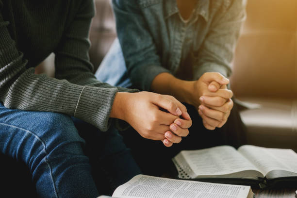 zwei frauen lesen und studieren bibel zu hause und beten zusammen. - bible stock-fotos und bilder